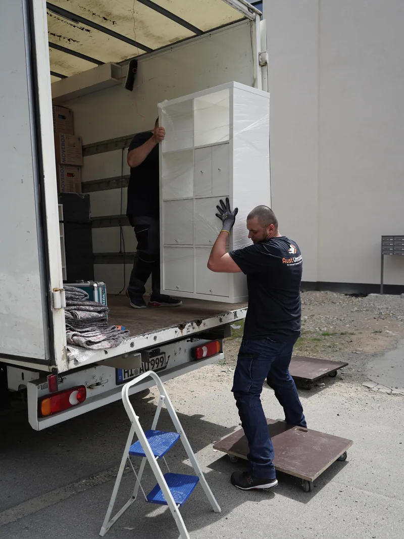 Aust Umzüge Mitarbeiter laden ein Möbelstück aus dem Umzugswagen